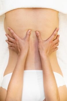 Top view of woman receiving a back massage in a physiotherapy center. Female patient is receiving treatment by professional therapist.. Young woman receiving a back massage in a spa center