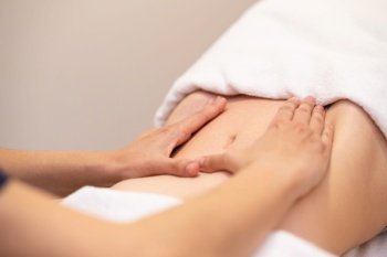 Woman receiving a belly massage at spa salon. Female patient is receiving treatment by professional osteopathy therapist.. Woman receiving a belly massage at spa salon