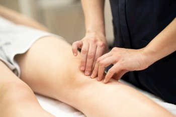 Female Physiotherapist woman doing a treatment on a young woman’s knee.. Physiotherapist woman doing a treatment on a woman’s knee.