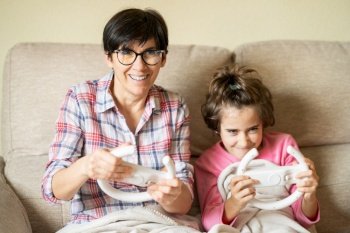 Mother and daughter playing video games at home with a wireless console. Mother and daughter playing video games at home