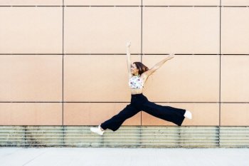 Happy young woman jumping in urban background. Geneneration Z girl. Happy young woman jumping in urban background