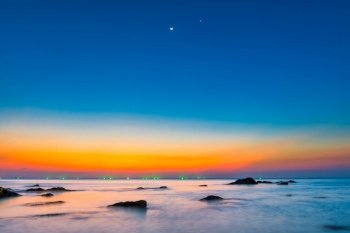 Sunset sea with rocks and sunset night landscape on dramatic sky under moon light