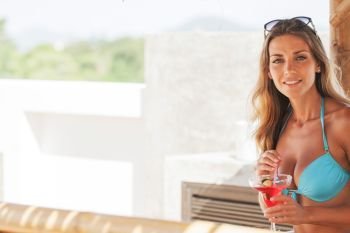 Girl in bikini on vacation drinking cocktail and smiling. Girl in bikini drinking cocktail