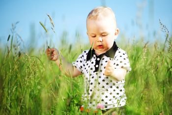Cute baby boy walking in grass rural meadow. Baby boy in grass