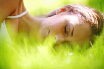 Beautiful young woman sleep on green spring grass. Woman sleep on grass