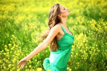 Young woman enjoy life dancing on oilseed flower field. Woman on oilseed field