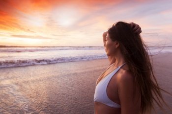 Beautiful fit woman on beach look at sunset time sea summer vacation. Woman in bikini by sea at sunset