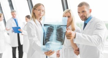 Team of experts doctors examining lungs X-ray report on hospital office meeting. Team of expert doctors with x-ray