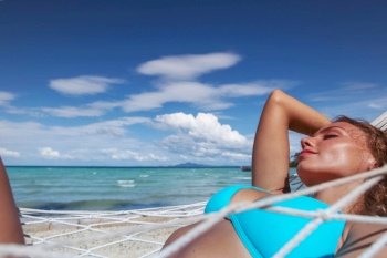 Girl in bikini relaxing in hammock on the beautiful paradise beach. Girl relaxing in hammock