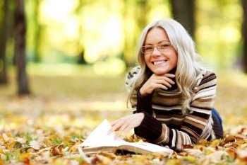 woman read the book in autumn park. woman read in park