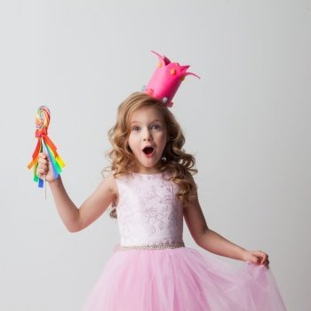 Beautiful excited candy princess girl in crown holding big lollipop. Candy princess girl in crown