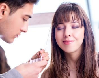 The man doing make-up for cute woman in beauty salon. Man doing make-up for cute woman in beauty salon
