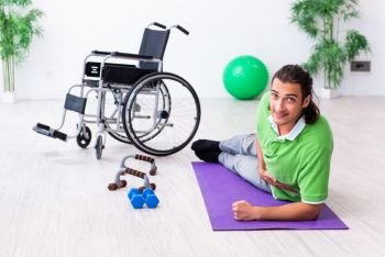 The young man in wheel-chair doing exercises indoors. Young man in wheel-chair doing exercises indoors