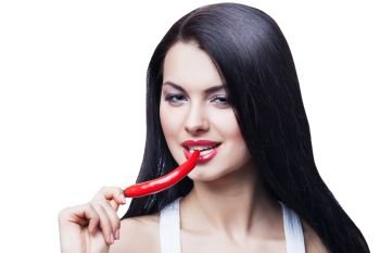 sexy brunette woman biting chili pepper on white background
