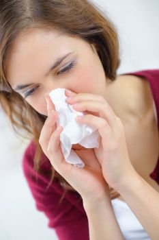 burnette woman blowing nose into tissue