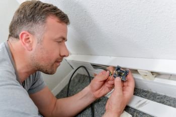 Man fitting electrical socket in skirting board