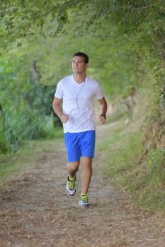 young handsome runner with earphones outside in nature