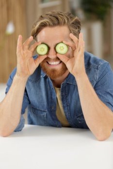 man holds cucumber on eyes