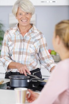 cheerful young woman cooking with elderly grandmother