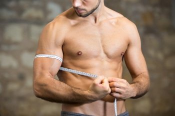 muscular man with measuring tape flexing biceps