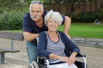 senior man and woman in wheelchair in park