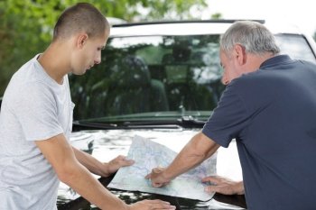father and son looking at map spread over car bonnet