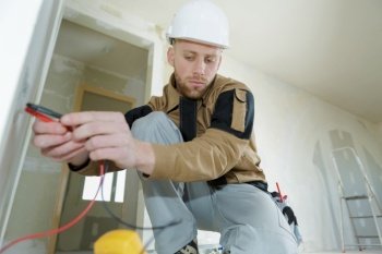 man wearing working on electrical wall socke