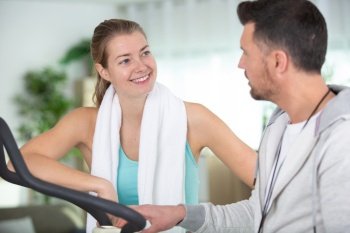 personal trainer advising woman using fitness equipment