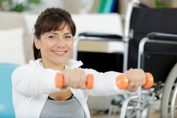 happy disabled woman doing exercises with dumbbells