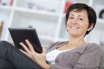 woman is relaxing and reading tablet on sofa