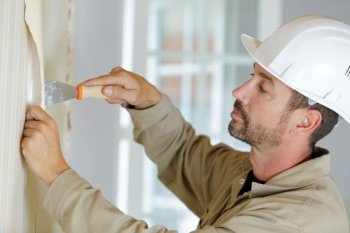 one painter worker peeling off wallpaper
