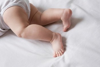 Baby lying on bed low section. Newborns
