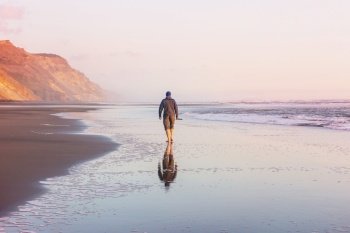 Man on ocean beach at sunset. Vacation concept background.