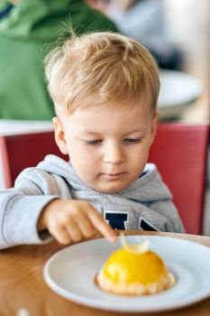 Two year old boy eating dessert in cafe