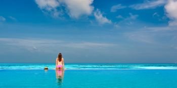 Woman relaxing in infinity swimming pool at Maldives
