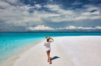 Woman with sun hat on tropical beach at Maldives