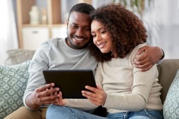 technology, internet and people concept - happy african american couple with tablet computer at home. african american couple with tablet pc at home