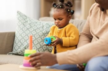 family, parenthood and people concept - african american father and baby daughter playing with toy blocks at home. african family playing with baby daughter at home