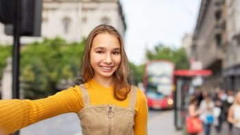 people concept - happy smiling young teenage girl taking selfie over london city street background. happy teenage girl taking selfie over london city