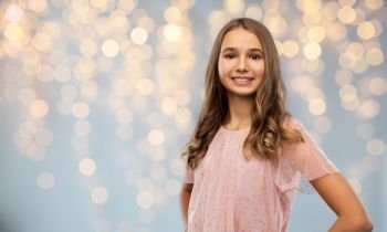 fashion and people concept - smiling young teenage girl in party dress over festive lights background. smiling teenage girl in party dress over lights