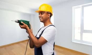 profession, construction and building - happy smiling indian worker or builder in helmet with electric drill or perforator over empty home or apartment room background. happy indian builder in helmet with electric drill