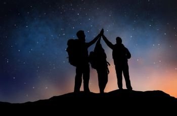 travel, hike and success concept - group of travelers or friends making high five gesture on edge of mountain over starry night sky or space background. travelers making high five over starry night sky