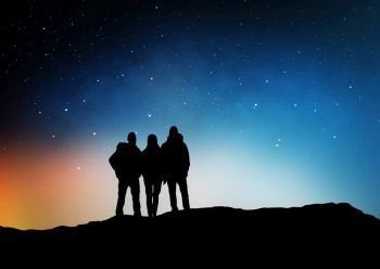 travel, hike and success concept - group of travelers or friends standing on edge of hill over starry night sky or space background. travelers or friends on edge over night sky