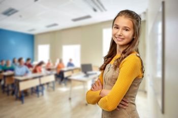 high school, education and people concept - smiling young teenage student girl with crossed arms over classroom background. smiling student girl with crossed arms at school