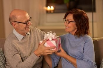 holidays and people concept - happy senior couple with gift box at home. happy senior couple with gift box at home