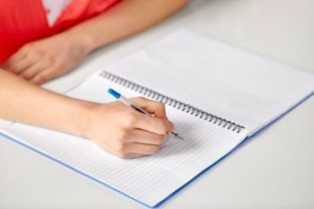 education, school and learning concept - hands of student girl with pen writing to notebook. hands of student girl with pen writing to notebook