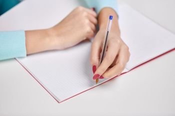 education, school and learning concept - hands of student girl with pen writing to notebook. hands of student girl with pen writing to notebook