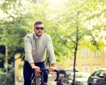 lifestyle, transport and people concept - young man in sunglasses riding bicycle on city street. young man in shades riding bicycle on city street