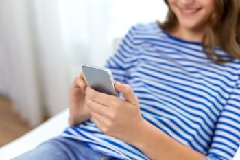 technology and people concept - close up of smiling teenage girl using smartphone at home. smiling teenage girl using smartphone at home