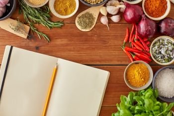 food, culinary and eating concept - notebook with pencil among different spices, onion, garlic with pine nuts and red hot chili peppers on wooden table. notebook with pencil among spices on wooden table